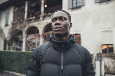 Portre genç Afrikalı adam tek başına duruyor ve daha ileriye bakıyor. 