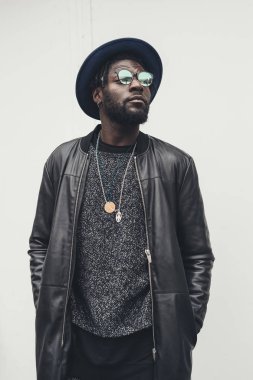 Genç Afrikalı bir adamın portresi. Tek başına duruyor ve başka tarafa bakıyor. 