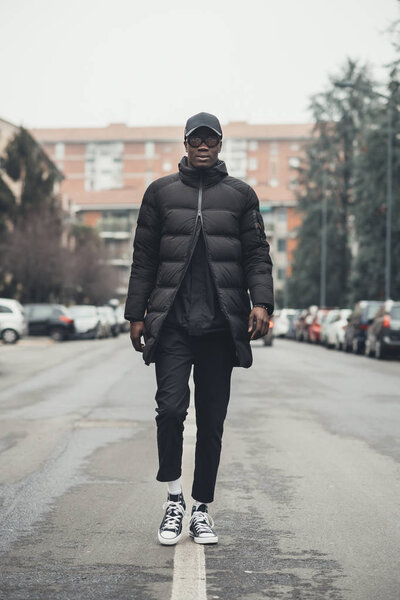 молодой чернокожий мужчина бегает по улице и смотрит на камеру
