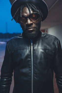 Portre genç siyah adam sokakta duruyor ve kameraya bakıyor.