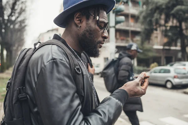 Retrato de un joven africano parado en la calle y fumando — Foto de Stock