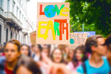 Grev protestolarında iklim değişikliği için pankart tutan insanların eğik duruşu - iklim politikalarında değişiklik olduğunu iddia eden eylemci
