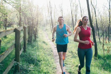 Genç bir çift arka planda birlikte koşuyor. Sportif, eğitimli, sağlıklı yaşam tarzı kavramı.