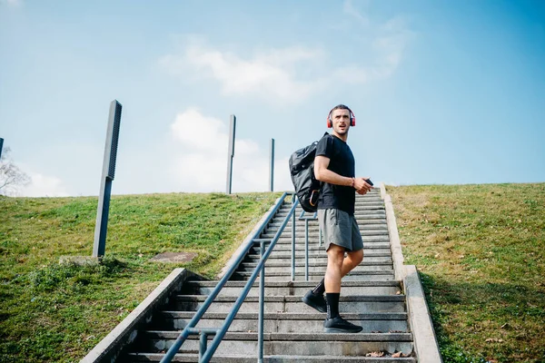 Genç Sportif Adam Merdivenlerde Müzik Dinliyor Sırtında Sırt Çantası Olan — Stok fotoğraf