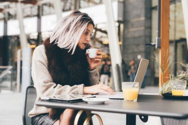 Barda bilgisayar kullanan serbest bir kadın - Kafkasyalı genç bir kadın uzaktan kahve içiyor - iş, internet, iş konsepti