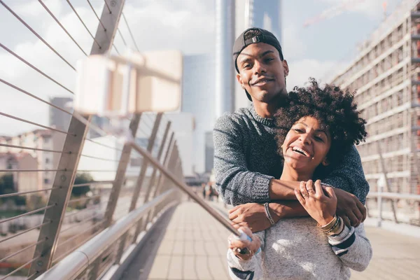 Black couple outdoor taking selfie using selfie stick - Deiverse man and woman hugging outdoor taking photo using smartphone - traveler, happiness, togetherness concept