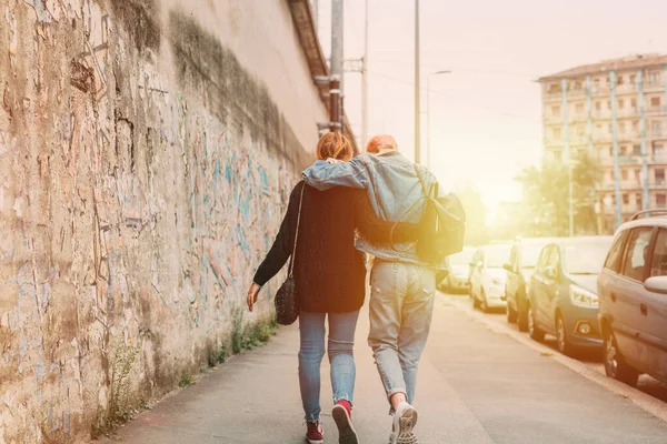 2人の若い女性が巨大な屋外を歩いています 姉妹が一緒に街を抱き合って歩く 肯定的な態度 自由の概念 — ストック写真