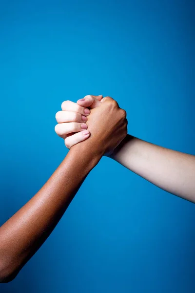 Black and white women hands handshake showing each other friendship and respect on blue background - Isolated diverse multiethnic female hands supporting - brotherhood, racism, equality concept