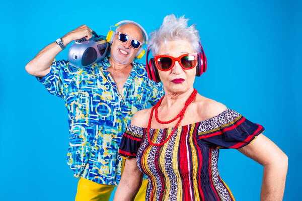 Couple of senior man and woman on blue background clubbing - Grandpa and grandma dancing isolated with stereo on holiday - technology, clubbing, having fun concept