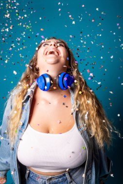 Siyahi kadın dans edip mavi arka planda konfeti yayarken eğleniyor - izole edilmiş genç kadın stüdyo çekimlerini kutluyor - kutlama, hevesli, neşeli konsept