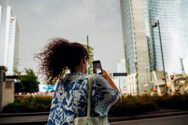 Genç melez kadın akıllı telefon kullanarak resim çekiyor çok ırklı kadın dışarıda selfie çekiyor sosyal ağ, anılar, teknoloji konsepti.