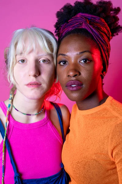 年轻的黑人女性和高加索女性的画像 不同的年轻女性在粉色背景下显得孤立无援 女性化的概念 — 图库照片