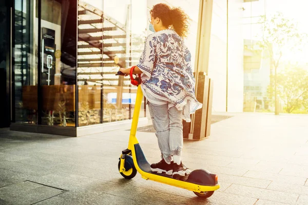 Young mixed woman riding electric scooter outdoors - Woman enjoying new electric mobility using kick scooter - green, transportation, eco friendly concept