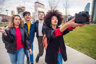 Multiethnic friends  walking outdoor taking selfie - Group of diverse friends having fun outdoor doing live on social media - friendship, vlogger, communication concept clipart