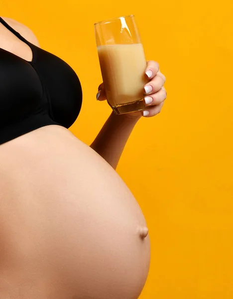 Unga gravida lyckliga modern kvinna glad leende dricka apelsinjuice på gula — Stockfoto