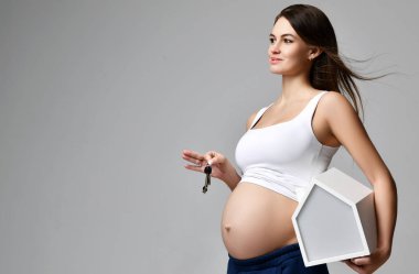 En iyi Beyaz gömlekli hamile kadın küçük Beyaz Saray ve anahtarları gri üzerine basılı tutun 