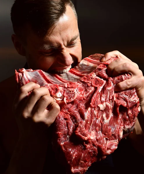 Strong sport man eat big beef ribs on dark kitchen background healthy eating concept