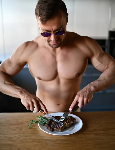 Homem pronto para comer cortado com garfo e faca grelhar bife em uma cozinha — Fotografia de Stock