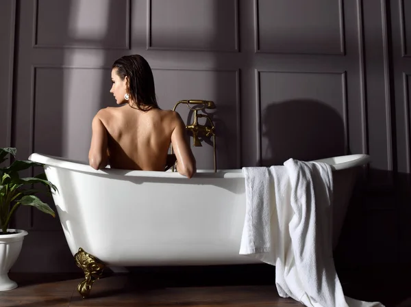 Jonge mooie vrouw zitten in de badkamer in de buurt van dure Bad Bad kijken naar de hoek op donker — Stockfoto