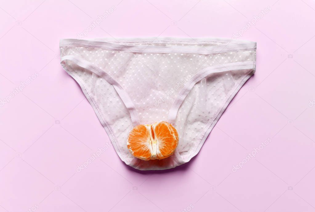 Body care gynecology and woman's health. Woman panties and half of tangerine fruit in an intimate part