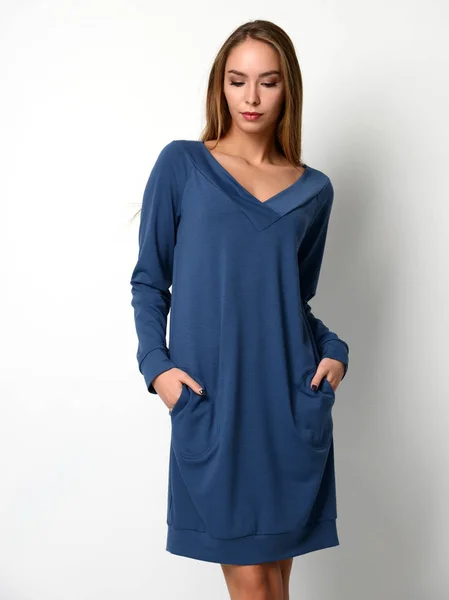 Junge schöne Frau posiert in neuer Mode blaues Winterkleid Bluse auf einem grauen — Stockfoto