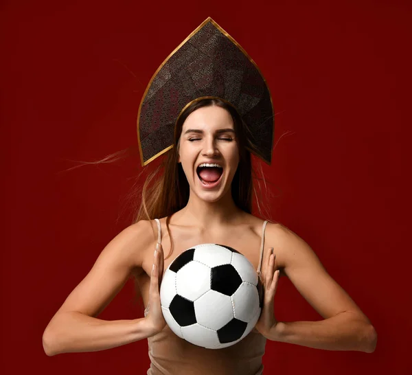 Estilo ruso Ventilador jugador de deporte mujer en kokoshnik sombrero celebrar pelota de fútbol feliz sonriente con espacio de copia de texto libre en rojo —  Fotos de Stock