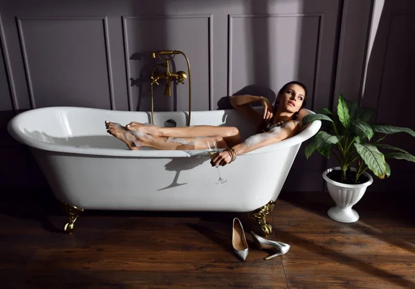 Banyoda karanlık köşede bakarak pahalı küvet banyo yakın oturan genç güzel kadın 