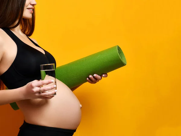 怀孕概念。孕妇饮水举行运动绿色瑜伽垫为锻炼和磁带措施 — 图库照片