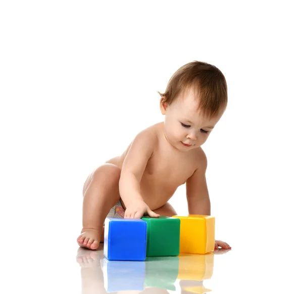 Infant child baby girl toddler playing holding green blue yellow bricks toys — Stock Photo, Image