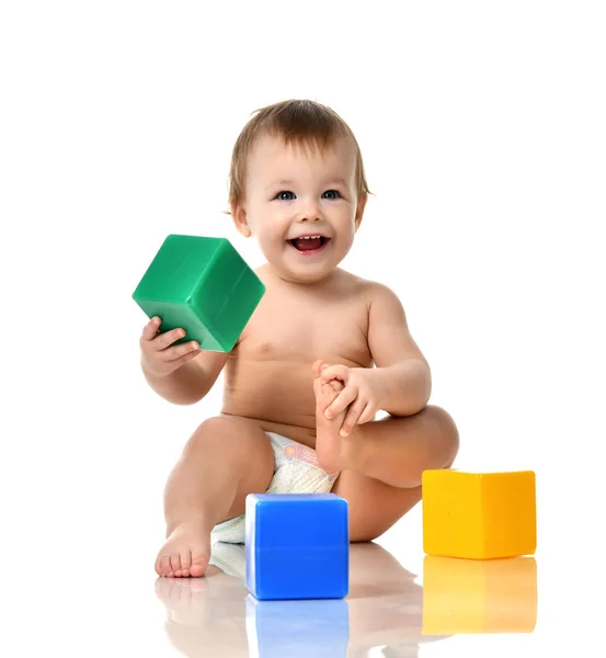 Infant child baby girl toddler playing holding green blue yellow bricks toys — Stock Photo, Image