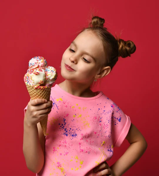 Bebek kız çocuk tutun büyük dondurma waffle koni ile kırmızı zemin üzerine yemek için ahududu mutlu gülümseyen hazır — Stok fotoğraf