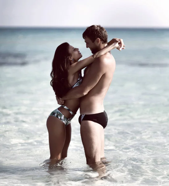 Щаслива весела пара цілується, обіймаючись бігом у морі разом. Романтичний відпочинок, медовий місяць кохання — стокове фото