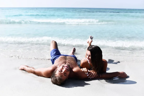 Feliz casal alegre se divertindo deitado na praia de areia costa do mar juntos. Férias românticas, amor de lua de mel — Fotografia de Stock