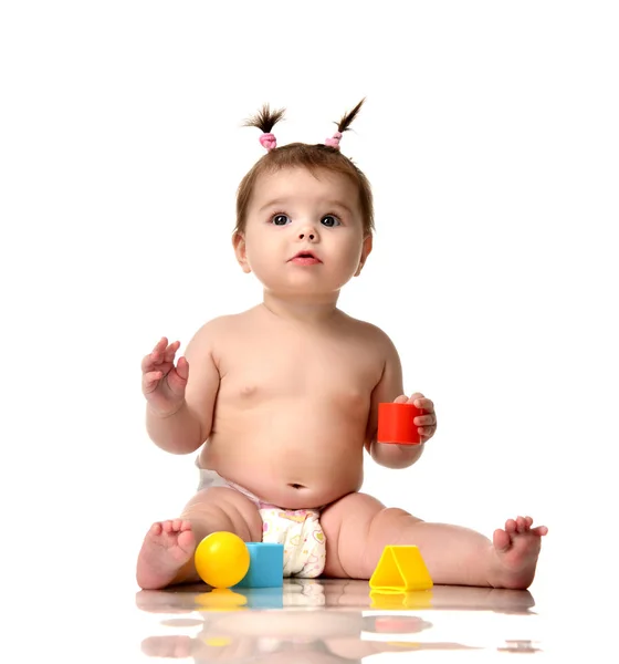 Nyfödda barn baby småbarn sitter i blöja med rött blått och gult tegel boll leksaker spela isolerad på en vit — Stockfoto
