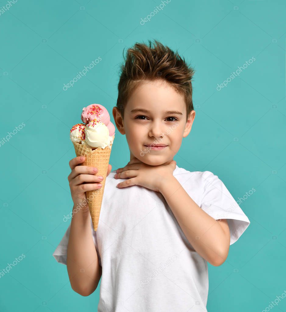 Baby boy kid hold strawberry vanilla ice cream in waffles cone hold hand near neck  sore throat on blue mint background