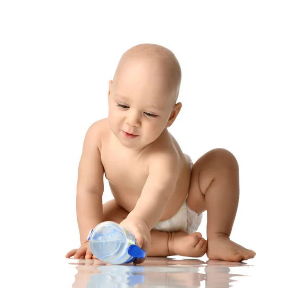 Infant child baby boy toddler sitting naked in diaper try to take a  bottle of water isolated on a white — Stock Photo, Image