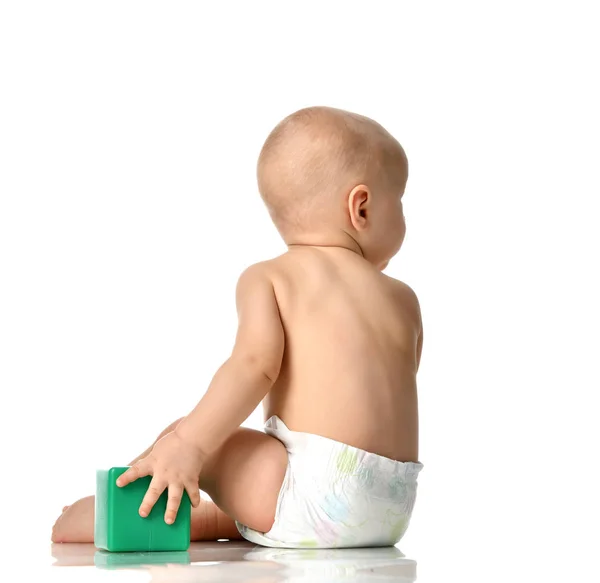 Child baby boy toddler sitting naked in diaper with green brick toy from behind rear backside view isolated on a white — Stock Photo, Image