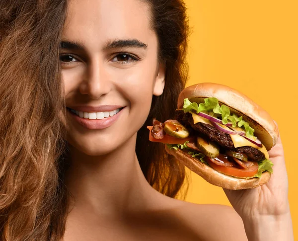 Mulher segurar grande carne cheeseburger sanduíche com fome boca feliz sorrindo no backgroun amarelo — Fotografia de Stock