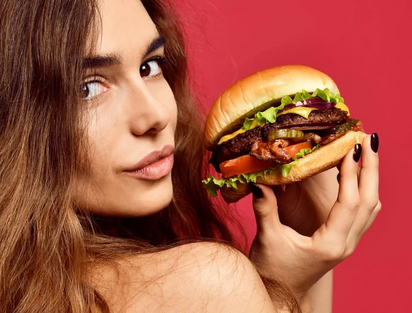Frau hält großes Rindfleisch-Burger-Sandwich mit hungrigem Mund glücklich in die Kamera auf rosa rotem Hintergrund — Stockfoto