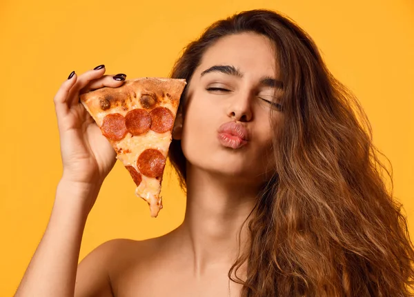 Giovane bella donna mangiare tenere salame piccante pizza slice show baciare segno con le labbra sul giallo — Foto Stock
