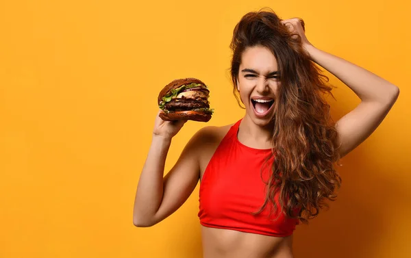 Vrouw houd grote barbecue Hamburger sandwich met hongerige mond gelukkig schreeuwen lachen op gele achtergrond — Stockfoto