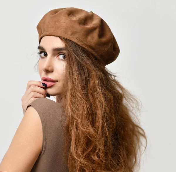 Молодая сексуальная брюнетка в коричневой беретной шляпе смотрит в угол — стоковое фото