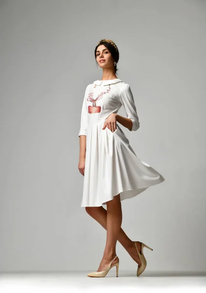 Женщина ходит в новом белом офисном платье нового образца на сером фоне — стоковое фото
