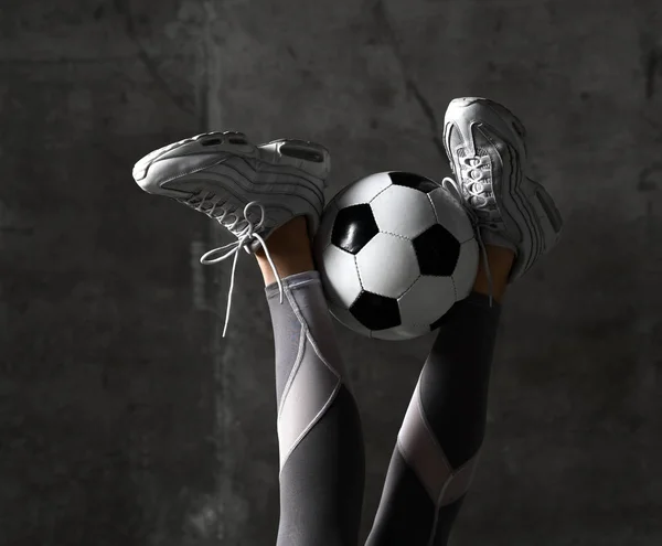 コンクリート壁のロフトにはサッカー ボールと女性の足 — ストック写真