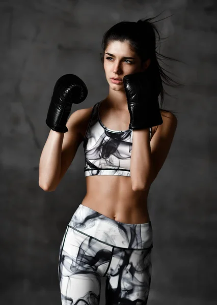 Young beautiful woman box trainer boxing in black gloves on concrete loft wall background — Stock Photo, Image