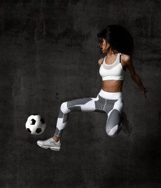 Kadın futbolcu atlar ve Orta Beton çatı duvar topu grev vurmak 