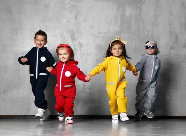 Feliz quatro crianças meninos e meninas se divertindo juntos na parede cinza — Fotografia de Stock