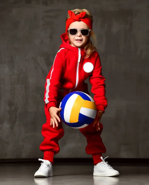 Voleybol kız çocuk tutun ve kırmızı kostümlü gri beton duvar topu tekmelemek — Stok fotoğraf