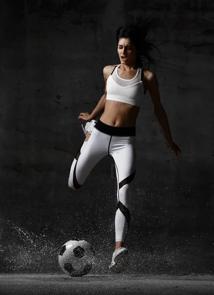 Mulher jogador correr salto e bater bola de futebol gritando com respingos de poeira — Fotografia de Stock