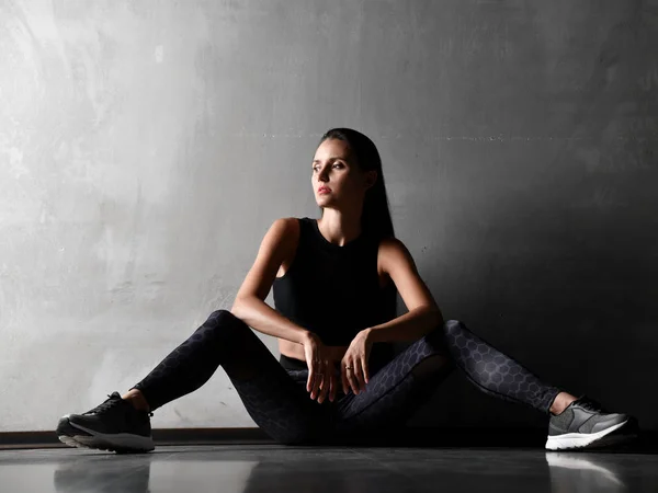Sportig kvinna efter gymnastik stretching fitness övningar träning sitter på golvet — Stockfoto